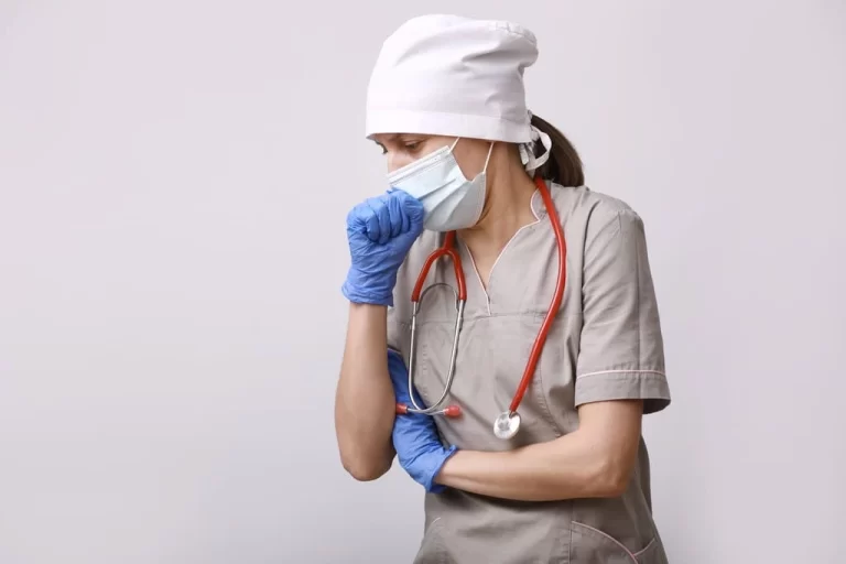 nurse in protective equipment coughing