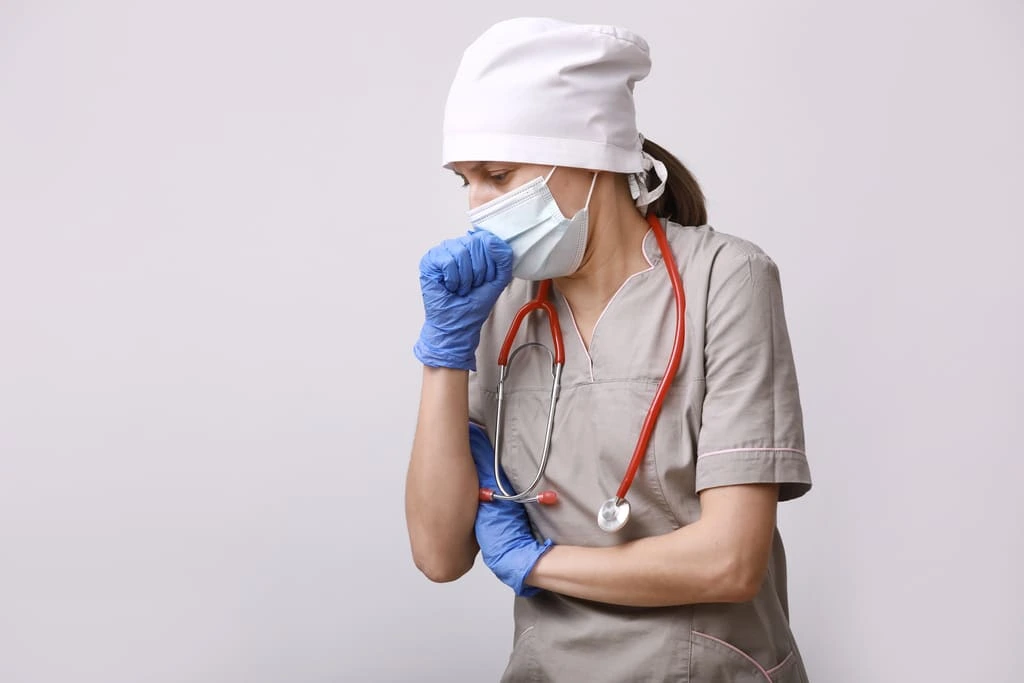 nurse in protective equipment coughing